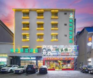 un grand bâtiment avec des voitures garées devant dans l'établissement GreenTree Alliance Sanya Jiyang District Yalongwan Road Hotel, à Da'ancun