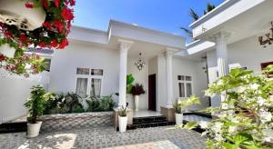 une maison blanche avec des plantes en pot dans la cour dans l'établissement Hoang Mai Hotel, à Ấp Thanh Sơn (1)