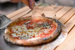 une personne qui coupe une pizza avec un coupe-pizza dans l'établissement Sunland S152 - Vacation STAY 54960v, à Mihara