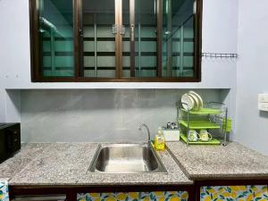 Una encimera de cocina con un fregadero y un armario. en Bird Hostel Chiangrai, en Chiang Rai