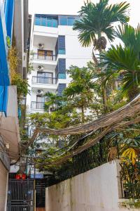 un grand bâtiment blanc avec des palmiers devant lui dans l'établissement Hera West Lake Apartment, à Hanoï