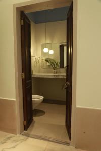 Un baño con inodoro, lavabo y espejo. en Kasumal, en Jaipur