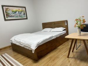 Un dormitorio con una cama con sábanas blancas y una mesa. en Home Dốc Mơ, en Xã Gia Tân