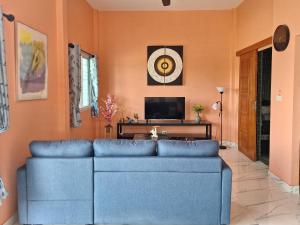 un salon avec un canapé bleu et une télévision dans l'établissement บ้านน้ำผึ้งโฮมสเตย์, à Suan Phueng