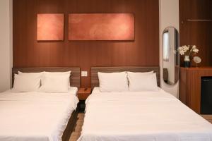 duas camas em um quarto de hotel com lençóis brancos em Chingu Boutique 2 em Vung Tau