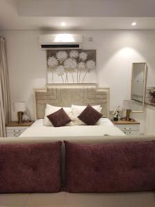 una camera da letto con un grande letto bianco con cuscini di Hawana Salalah Rosely Studio a Salalah