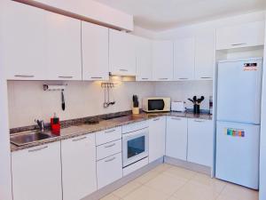 卡勒达德福斯特Casita Playa Castillo 3A的白色的厨房配有白色橱柜和冰箱。
