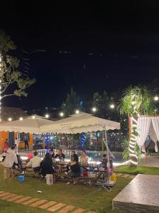 Hồ Bình Yên Homestay&Coffee-BBQ في Plei Kơtêng: مجموعة من الناس يجلسون تحت خيمة في الليل