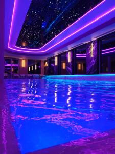 a swimming pool in a hotel with purple and blue lighting at Rezydencja AMBRE in Łeba