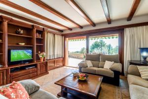 ein Wohnzimmer mit Sofa und Fernseher in der Unterkunft Can Xilla by Sealand Villas in Alcanada