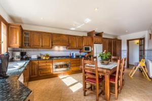 eine Küche mit Holzschränken und einem Tisch mit Stühlen in der Unterkunft Can Xilla by Sealand Villas in Alcanada