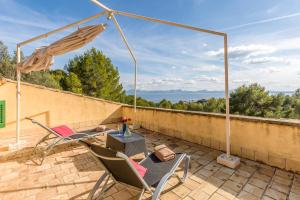 eine Terrasse mit 2 Stühlen, einem Tisch und einem Sonnenschirm in der Unterkunft Can Xilla by Sealand Villas in Alcanada