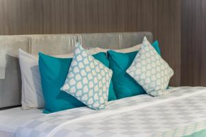 a bed with blue and white pillows on it at Bedrock Hotel Kuta in Kuta