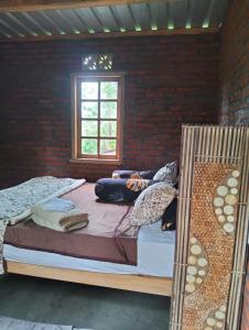 a bedroom with two beds and a brick wall at Nostalgia Camping Home in Selemadeg