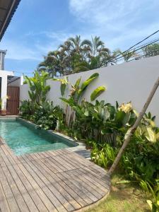 Un camino de madera que conduce a una piscina en un jardín. en Villa Mewangi by SooBali Private Pool in Sanur, en Sanur