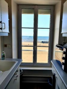 a kitchen with a window with a view of the beach at Le Phoenix 449 , vue mer, 2 chambres in Arromanches-les-Bains