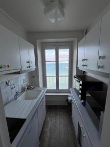 a kitchen with a sink and a large window at Le Phoenix 449 , vue mer, 2 chambres in Arromanches-les-Bains