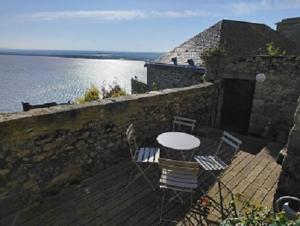 a table and chairs on a wooden deck next to the water at Chez Adèle, au pied de l'Abbaye in Le Mont Saint Michel