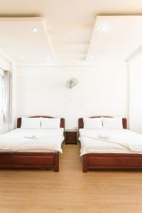 2 Betten in einem Zimmer mit weißen Wänden und Holzböden in der Unterkunft Thiên Hà Hotel in Ho-Chi-Minh-Stadt + 10 Fotos
