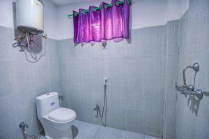 Un baño con inodoro y ducha con cortina morada. en Gairibari Resort, en Jhawāni