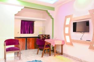 Una habitación con una mesa y sillas y un televisor. en R mansion, en Calangute