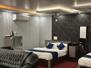 a bedroom with two beds and a leather couch at Thottunkal Tourist home in Kadavoor