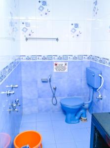 Un baño con inodoro azul y ducha. en R mansion, en Calangute