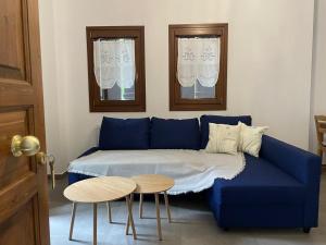 ein blaues Sofa mit einem Tisch und zwei Fenstern in der Unterkunft Pelion Bloom in Zagora
