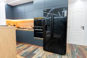 einen schwarzen Kühlschrank in einer Küche mit blauen Schränken in der Unterkunft VNS LUXURY STAY apartment in Târgovişte