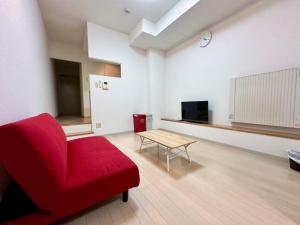 Una sala de estar con una silla roja y una mesa. en 503好立地で札幌駅徒歩7分と大通駅徒歩6分で都心を満喫でき綺麗な部屋で快適が生活が実現, en Sapporo