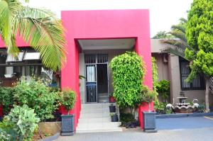 ein rosa Haus mit einer schwarzen Tür in der Unterkunft RAMATA GUEST HOUSE in Pretoria
