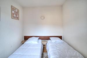 two beds in a room with white walls at Résidence La Chapelle - Cœur de station in Lélex