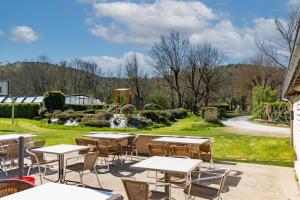 eine Terrasse mit Tischen und Stühlen sowie einen Garten in der Unterkunft Mobilhome Malaga Climatisé 31 in Saint-Martial-de-Nabirat