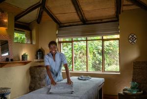 a woman standing next to a table in a room at Virunga Lodge in Nkumba