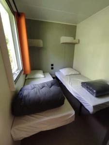 2 Betten in einem Zimmer mit Fenster in der Unterkunft Mobilhome Agora climatisé 50 in Saint-Martial-de-Nabirat