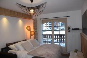 a bedroom with a bed and a large window at Centre, Pistes à pied, Vue magnifique, Calme, Tout renové, Grande terrasse in Les Gets
