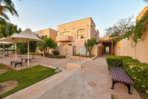 einen Park mit einer Bank, einem Regenschirm und einem Gebäude in der Unterkunft Harf-281 4 BEDROOMS - Raha Gardens AD in Abu Dhabi