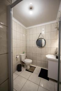 a bathroom with a toilet and a sink and a mirror at Serenity on Geelhaak in Kempton Park +26 photos
