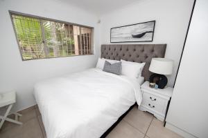 a white bedroom with a bed and a window at Serenity on Geelhaak in Kempton Park