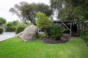 a garden with a large rock and a building at Serenity on Geelhaak in Kempton Park