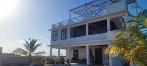 a white house with a palm tree in front of it at Villa Katerina - Paje in Paje