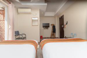 two beds in a room with a tv and a bedroom at Trishuli Riverside Resort in Benighāt