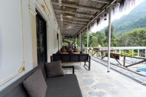 a porch with a couch and a view of the mountains at Trishuli Riverside Resort in Benighāt