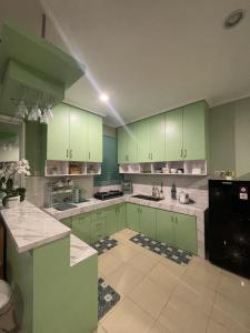 a kitchen with green cabinets and white counter tops at Green Love Villa in Pasirmuncang 1