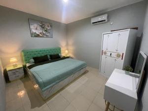 a bedroom with a bed with a turquoise headboard at Green Love Villa in Pasirmuncang 1