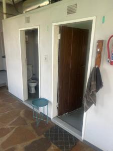 a bathroom with a door and a table and a toilet at The Cargo Club Guesthouse in Ventersburg