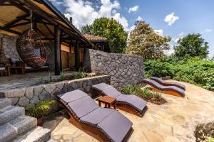 a patio with lounge chairs and a stone wall at Virunga Lodge in Nkumba +16 photos