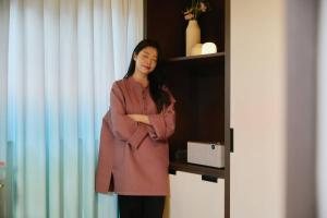 a woman standing in front of a shelf with her arms crossed at Stay Passport Nagoya Ryokan Anyang Pyeongchon in Anyang
