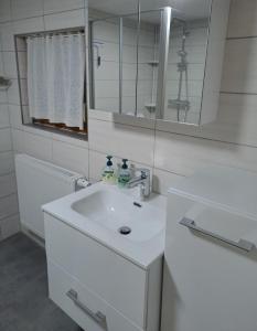une salle de bain blanche avec un lavabo et un miroir dans l'établissement An-der-Stadtmauer, à Fladungen