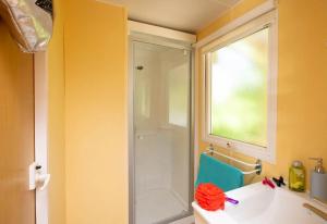 a bathroom with a shower and a sink and a window at ZEcamping 4 étoiles familial - parc aqua et soirées animées in Murol